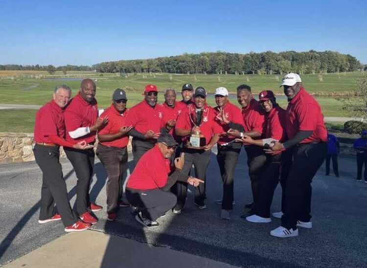 Kappa Alpha Psi golfers in red celebrating with the Cup on the clubhouse patio