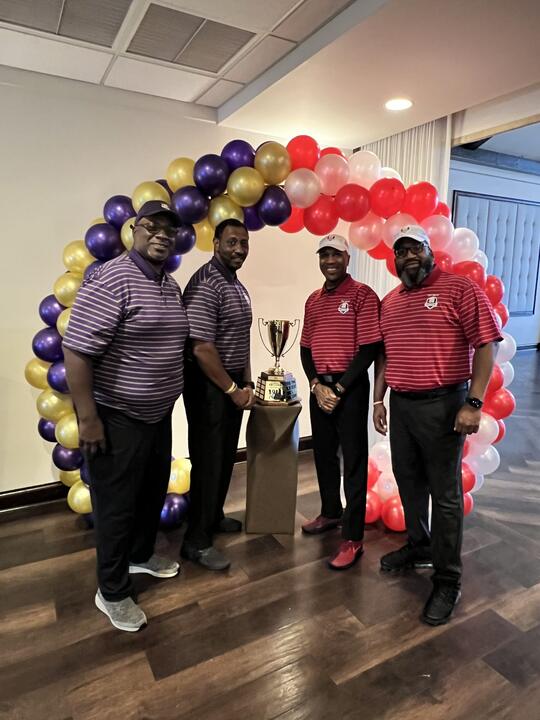 Golfers under a red and purple balloon arch